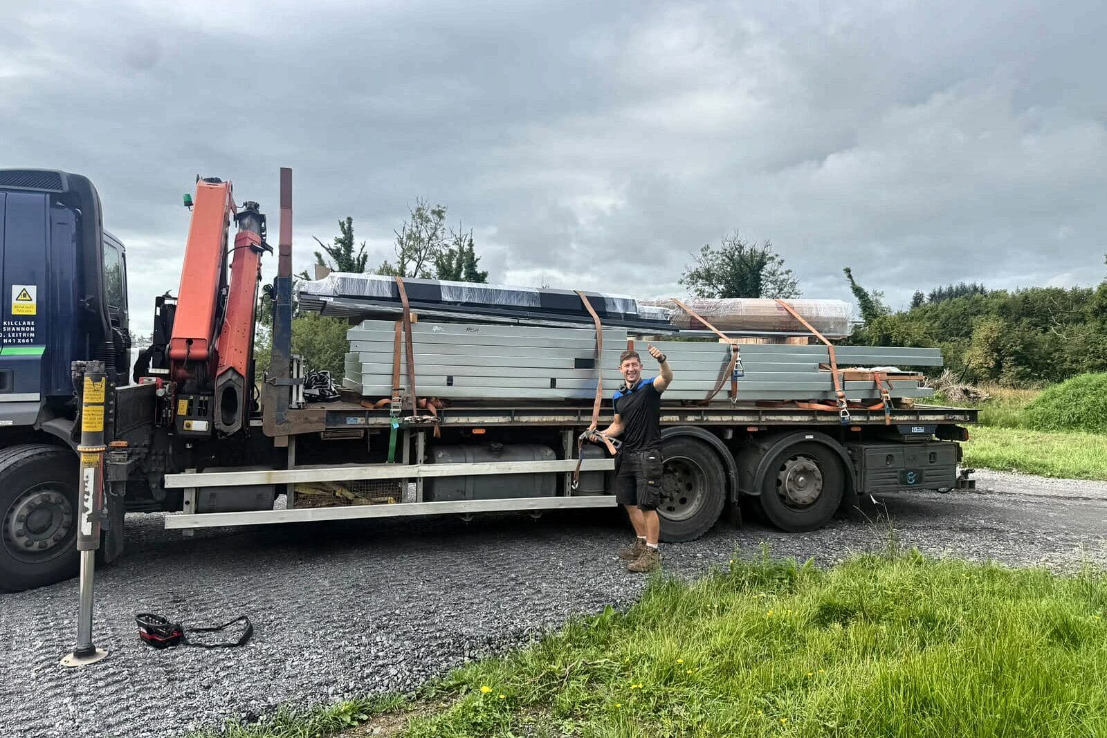 Lorry with a crane arm, loaded with steel for a shed