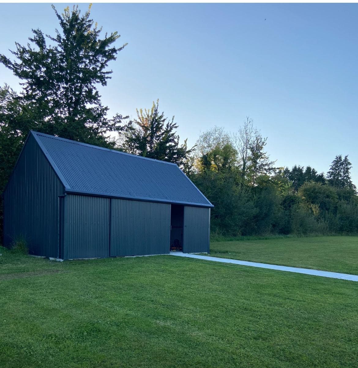A charcoal steel shed in a lush Irish garden at dusk